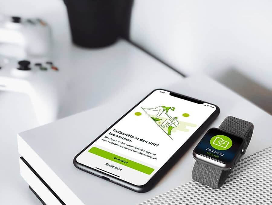 Digitale-Versorgung-Gesetz, Smartphone mit digitaler Gesundheitsanwendung liegt neben Smartwatch mit der gleichen Anwendung auf einer Konsole